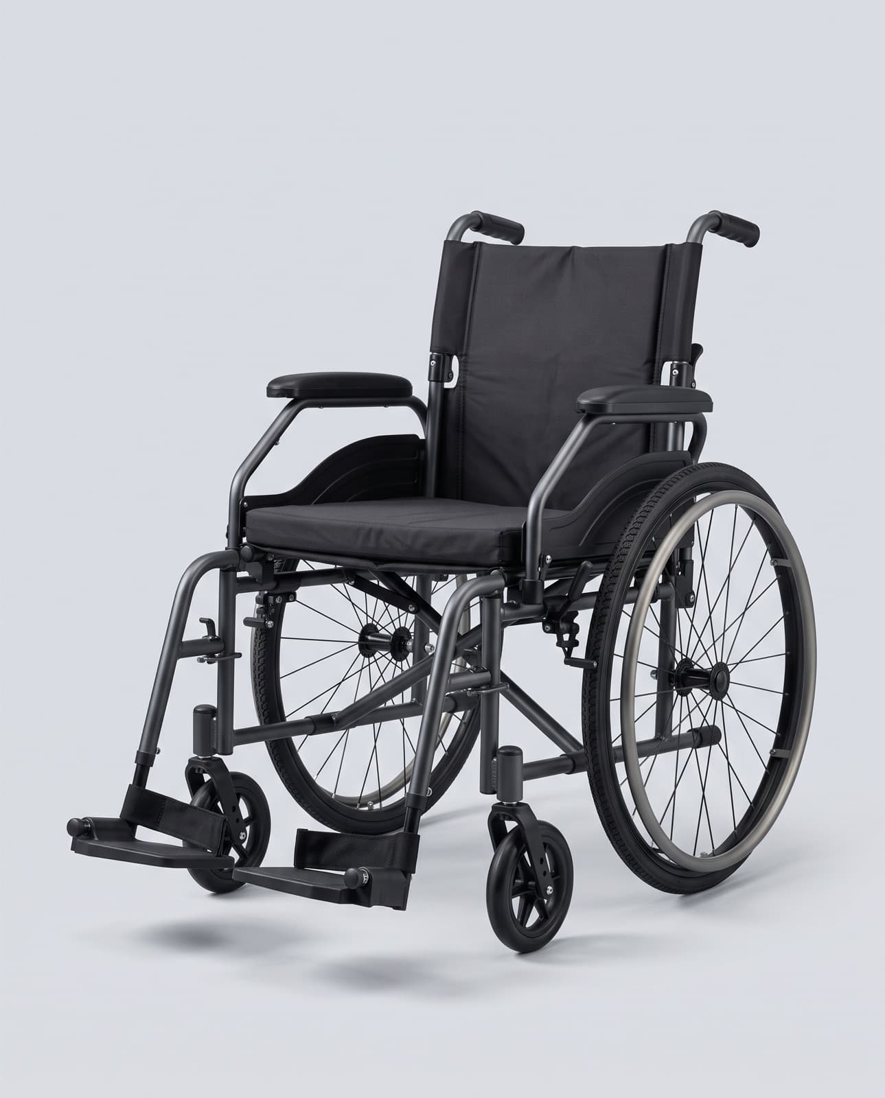 Fauteuil roulant pliant à châssis anthracite, assise noire et grandes roues à mains courantes grises, sur fond gris clair